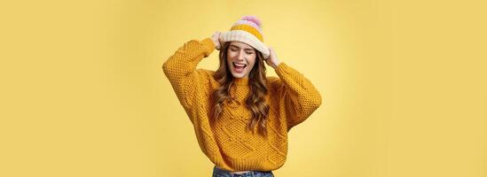 Wild rebellious carefree good-looking stylish caucasian woman having fun screaming out loud careless close eyes touching hat dancing singing favorite music listening songs dress-up university photo