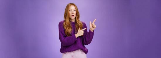 Stunned girl asking friend if she saw it drop jaw from stupor and amazement popping eyes at camera after witnessing shocking revelation pointing questioned at upper left corner over purple wall photo
