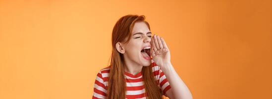 Hey where are you. Cute carefree redhead funny girl hold hand near opened mouth turn left close eyes, yelling out loud, searching someone, calling friend come upstairs, look for person distance photo