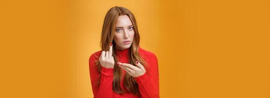 Redhead girl asking where wedding ring being fed up waiting proposal extending finger and pointing at it questioned and pissed having argument with boyfriend over orange background photo