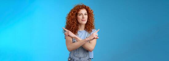 Curious creative redhead attractive modern young curly-haired female look intrigued pointing sideways left right squinting camera asking advice making choice deciding which product blue background photo