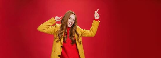 Hey dancing all night. Portrait of cheerful and excited ginger girl having fun as feeling happy and delighted of bright day moving to rhythm of music with disco moves and smiling broadly at camera photo