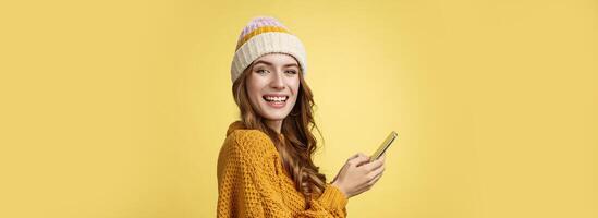 Profile shot entertained charming young woman playing mobile phone holding smartphone turning camera delighted having fun using cool app editing pics travel blogger messaging posting online photo