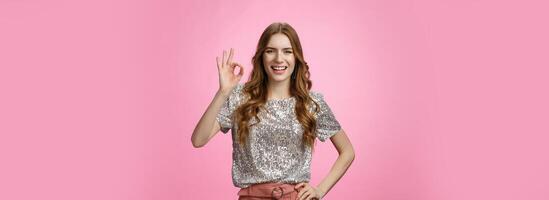 Okay got it. Charming friendly-looking outgoing glamour young attractive woman show ok no problem gesture smiling assured confident everything perfect, recommend excellent service, pink background photo