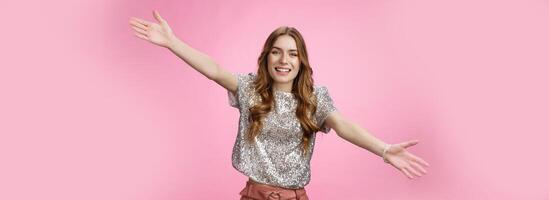 Come into my arms. Portrait friendly outgoing charming cute caucasian female wearing glittering blouse extend arms sideways wanna embrace cuddle friend welcoming hugging guests, smiling broadly photo