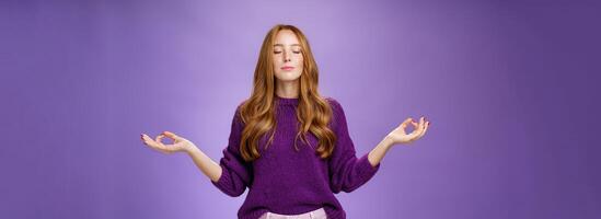 Sound mind in body. Peaceful and happy attractive female with red hair and freckles close eyes and smile from calm and relieved feelings as meditating in lotus pose with mudra gesture, doing yoga photo