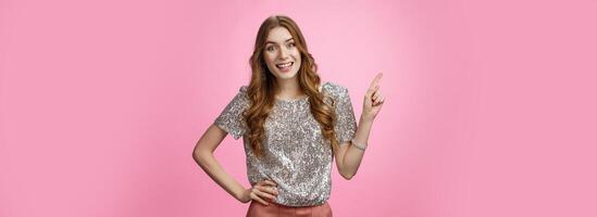 Attractive outgoing party girl gossiping smiling excited like socialize have pleasant conversation gesturing pointing upper left corner discussing copy space, standing pleased pink background photo