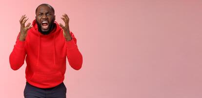 Guy hates subway. Irritated hungry mad bearded african-american man yelling squeez fists frowning grimacing shouting losing temper furiously staring camera go crazy insane, standing pink background photo
