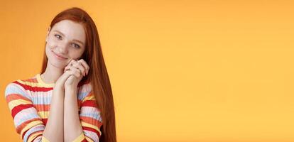 Dreamy sensual romantic young passionate redhead girlfriend melt heart feel sympathy joy receive sweet tender present lean palms smiling grateful gladly accept nice lovely gift, orange background photo