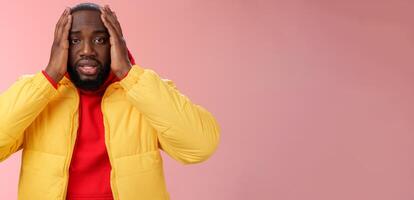 Shocked upset african-american bearded guy feel regret stunned hear terrible news hold hands head widen eyes stupor standing speechless troubled, look perplexed terribly sad, pink background photo