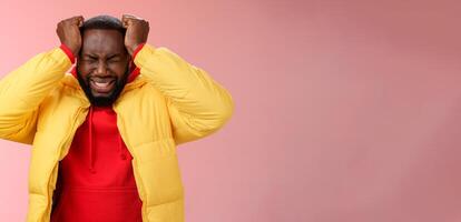 Depressed heartbroken black bearded boyfriend go crazy pissed squeez head frowning squinting clenching teeth painful feeling inside standing devastated distressed pink background suffering headache photo