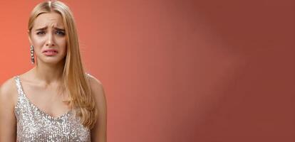 Disappointed complaining cute blond woman in silver stylish dress grimacing frowning upset have bad day pouting pity standing displeased unhappy heartbroken everything bad, red background photo