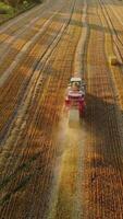Aerial view on the field and tractor pressing hay. Agricultural machine is baling dried grass into square bale on the natural field background. Vertical video