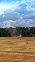 Aerial view on the yellow field with straw bales. Seasonal works in the rural place. Many round bundles of hay laying on the field. Camera moves back. Vertical video