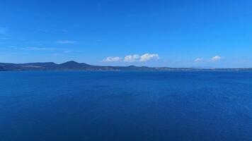 Calm lake surface reflecting blue sky with mountains in background video