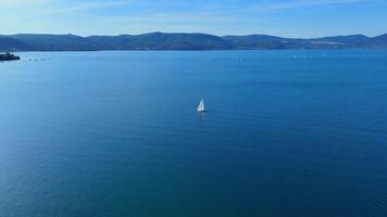 Sailboat navigating calm waters with lush green hills in background video