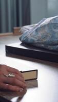 Tailor is opening box with beautiful sewing buttons on the background of workshop. Dressmaker's hands taking box with different buttons for sewing in atelier. Vertical video