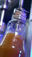 Few glass bottles being filled full with freshly-made juice. Automated technological process of juice manufacturing. Close up. Vertical video
