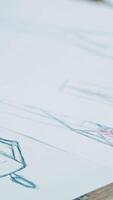 Different stylish sketches of clothes on the sheets of papers lying on the table. A lot of creative works of a fashionable designer painted on papers. Vertical video
