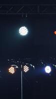 Dark stage with colorful spotlights or several bright projectors. Different projectors with lighting effects on scene in the evening. Vertical video
