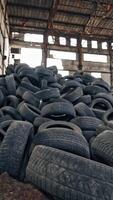 Black junk tires lying on the floor in the old abandoned building. Many used rubber tires from different vehicles are on a desolate plant inside. Vertical video