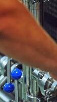 Worker switches on automated machine in a modern plant. Worker turning on metal tool to start the work of a modernized machine in a dairy factory. Close-up. Vertical video