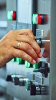 Worker's hand pressing buttons of a mechanical machine at manufacturing plant. Automated equipment in a modernized dairy factory. Vertical video