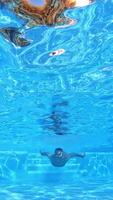 Handsome man swimming underwater. Jumping into the pool on a sunny day. Slow motion Vertical video