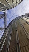 Aluminum containers for storing grains. Exterior of large metal elevators. Close-up. View from below. Camera motion around. Vertical video