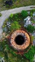 Old industrial chimney. Brick pipe of long built on the desolate factory position. Top aerial view. Vertical video
