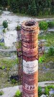 Abandoned pipe among nature. Old brick tower surrounded by green trees in summer. Camera moves top down. Vertical video