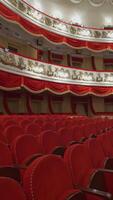 Rows of red chairs in theater hall. Beautiful empty opera house without audience at lockdown time. World crisis, financial losses, consequences of the pandemic. Vertical video