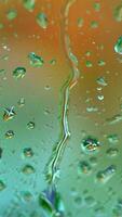 Raindrops on blur colorful background. Large drops flowing on glass window slowly in rainy weather. Close-up. Vertical video