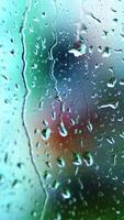 Wet window with raindrops. Water drops moving down on glass window on blur view background. Close-up. Vertical video
