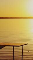 Silhouette of a boy goes on the bridge over the lake and sees at the sunset. Slow motion of the kid on empty bridge walking to watch a beautiful sunset near the river Vertical video