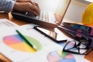 Hands of woman working with laptop and trade data chart document on office desk. photo