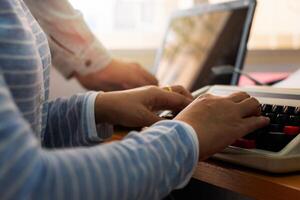 Hands of two workmate typing on working desk in office. photo