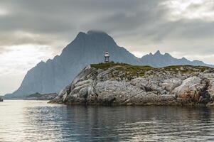 Norwegian seascape, lighthouse on the island, rocky coast with dramatic skies, the sun breaks through the clouds, sheer cliffs, small islands illuminated by the sun photo