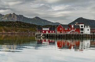 a classical building for stopping yacht travellers, fishing house of red color on the coast on Lofoten Islands, classic norwegian landscape, rocky coast with dramatic sky photo