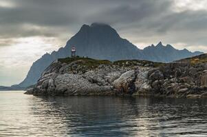 Norwegian seascape, lighthouse on the island, rocky coast with dramatic skies, the sun breaks through the clouds, sheer cliffs, small islands illuminated by the sun photo