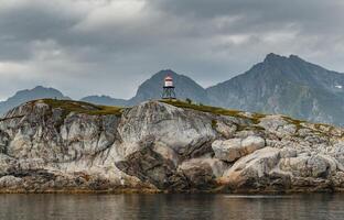 Norwegian seascape, lighthouse on the island, rocky coast with dramatic skies, the sun breaks through the clouds, sheer cliffs, small islands illuminated by the sun photo