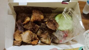 Crispy pork belly with cucumber and chili in a white takeout container. photo