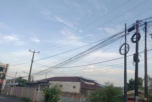 A view of power lines and utility poles against a blue sky with white clouds. photo
