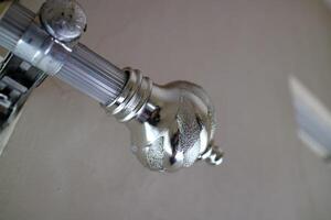 The curtain pole end cap with a round tapered shape with a chrome color, made of plastic photo