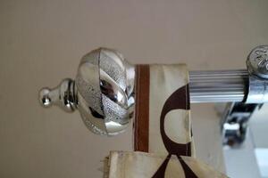 The curtain pole end cap with a round tapered shape with a chrome color, made of plastic photo