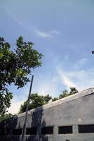 A view of a house wall with several air vents. Above it there is a view of the bright blue sky photo