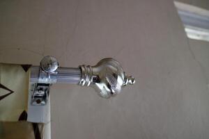 The curtain pole end cap with a round tapered shape with a chrome color, made of plastic photo
