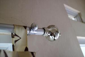 The curtain pole end cap with a round tapered shape with a chrome color, made of plastic photo