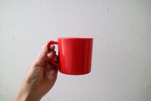 A asian hand holding a red cup or mug on a plain white background photo
