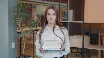 Portrait of a schoolboy of the senior classes with books in hands in a school class. video